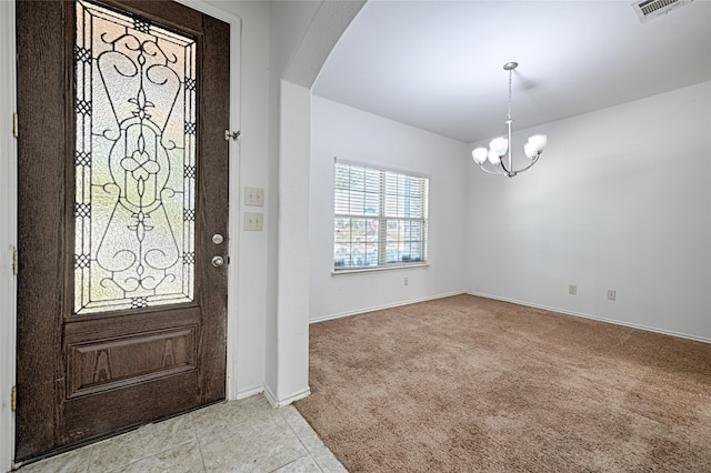 foyer featuring light carpet and a chandelier