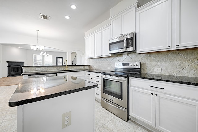 kitchen featuring white cabinets, hanging light fixtures, stainless steel appliances, sink, and a center island