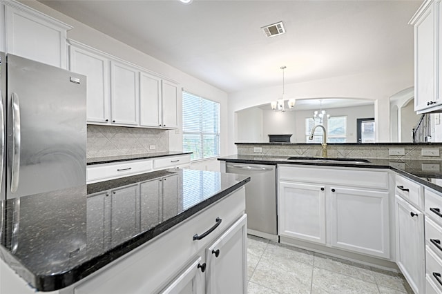 kitchen featuring hanging light fixtures, stainless steel appliances, sink, a chandelier, and white cabinetry