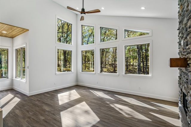 unfurnished sunroom featuring ceiling fan, a stone fireplace, and vaulted ceiling