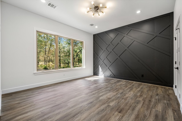 empty room featuring a notable chandelier and dark hardwood / wood-style flooring