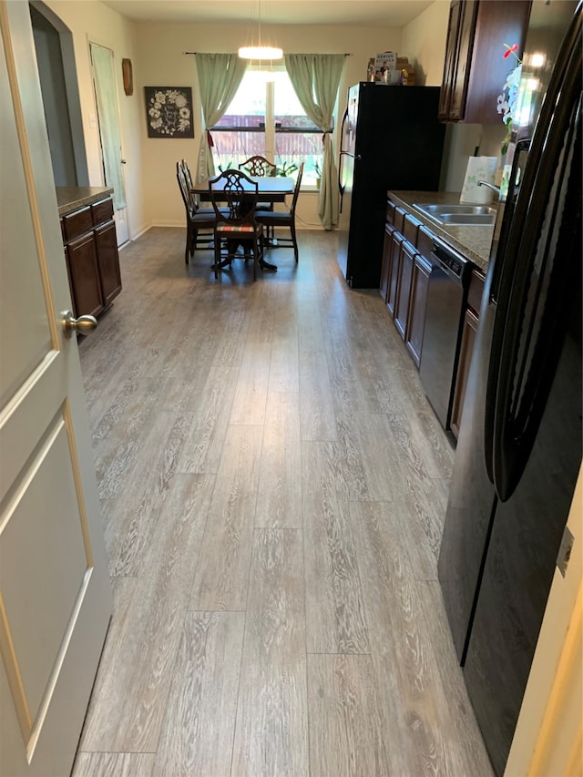 kitchen featuring light hardwood / wood-style floors, dishwasher, dark brown cabinetry, and black fridge