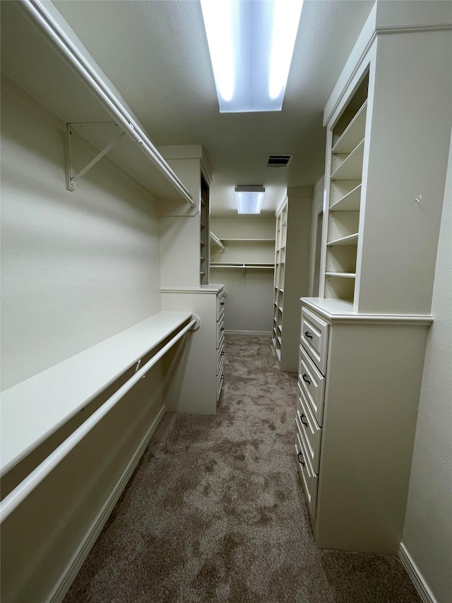 spacious closet with visible vents and dark colored carpet