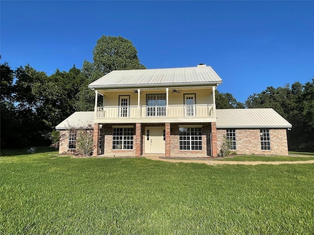 view of front of property with a balcony, a front yard, and ceiling fan