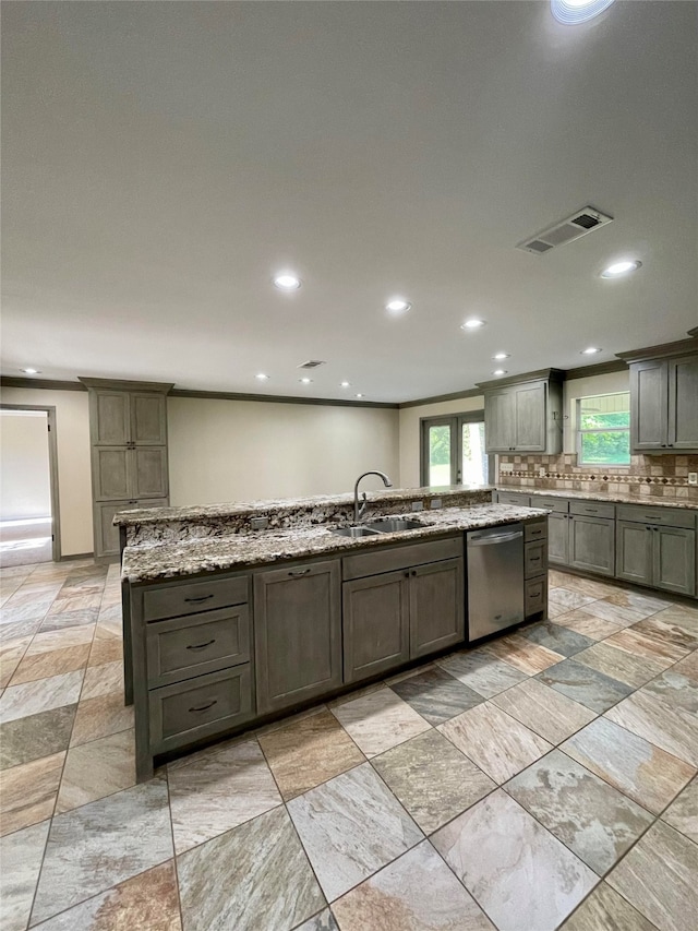 kitchen with tasteful backsplash, visible vents, a kitchen island with sink, a sink, and dishwasher