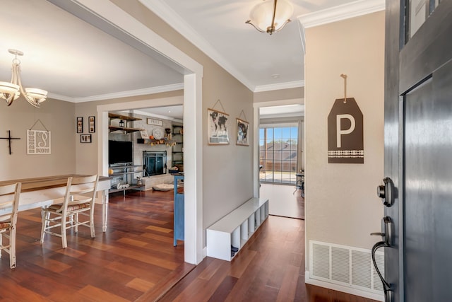 entrance foyer featuring crown molding, dark hardwood / wood-style floors, and a chandelier