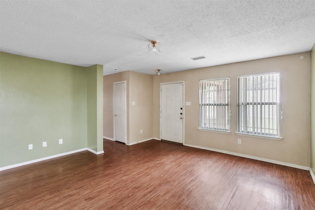 unfurnished room with a textured ceiling and dark hardwood / wood-style flooring