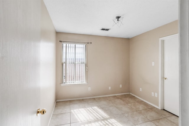 empty room featuring a textured ceiling and light tile patterned floors