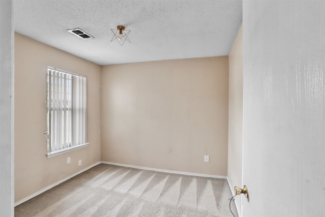 empty room with light carpet and a textured ceiling