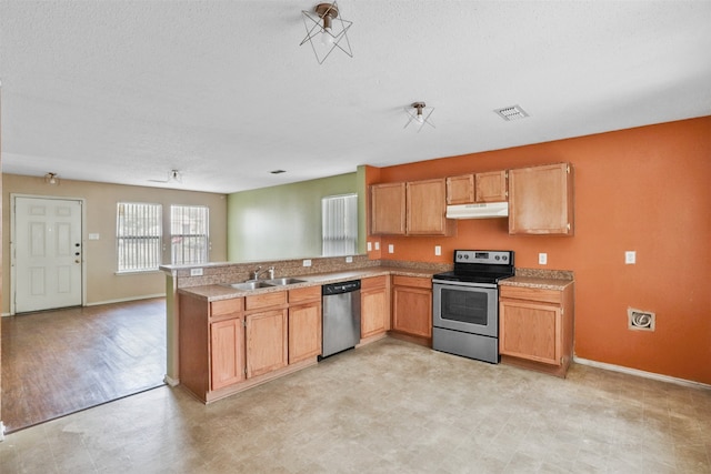 kitchen with kitchen peninsula, appliances with stainless steel finishes, a textured ceiling, light hardwood / wood-style floors, and sink