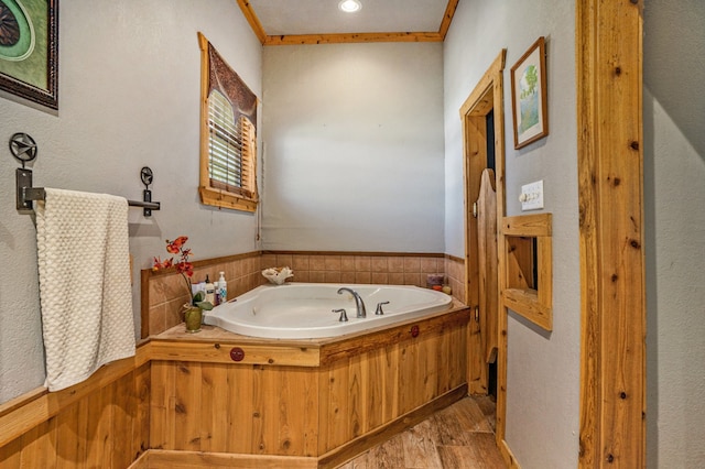 bathroom featuring crown molding, a tub to relax in, and hardwood / wood-style floors