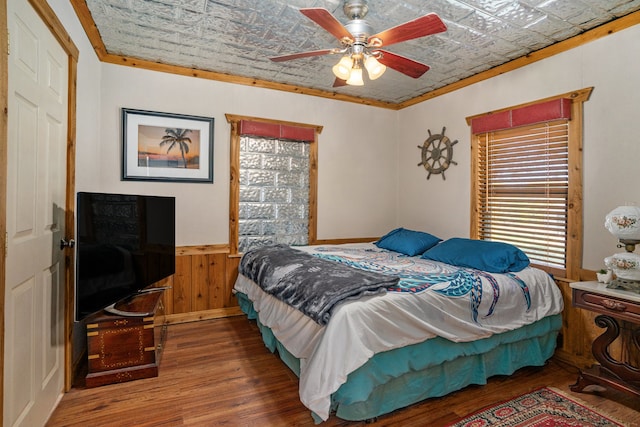 bedroom featuring crown molding, wood walls, ceiling fan, and hardwood / wood-style flooring