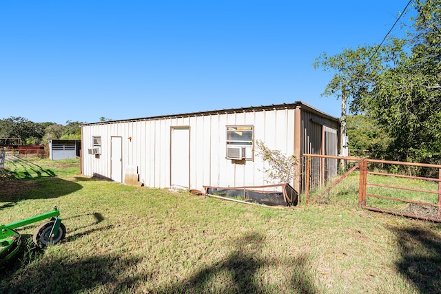 view of outbuilding with cooling unit and a lawn