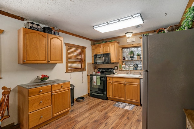 kitchen featuring a textured ceiling, sink, light hardwood / wood-style flooring, and black appliances