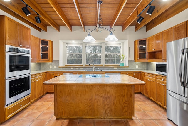 kitchen with tile countertops, a center island, hanging light fixtures, and stainless steel appliances