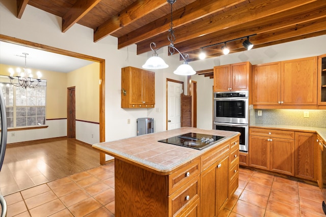 kitchen with hanging light fixtures, a kitchen island, black electric cooktop, light tile patterned flooring, and double oven