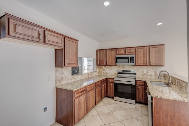 kitchen with tasteful backsplash, light tile patterned floors, appliances with stainless steel finishes, light stone countertops, and sink