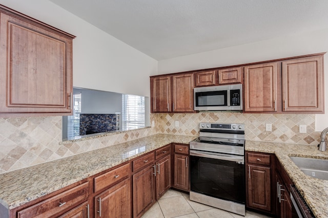 kitchen featuring stainless steel appliances, sink, light tile patterned floors, light stone counters, and tasteful backsplash