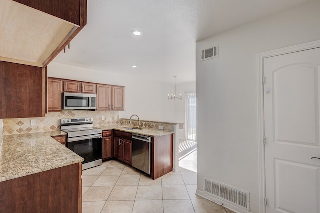 kitchen featuring kitchen peninsula, stainless steel appliances, sink, decorative light fixtures, and light tile patterned floors