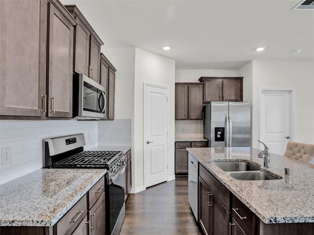 kitchen with a kitchen island with sink, sink, backsplash, and stainless steel appliances