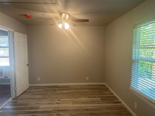 empty room with ceiling fan, a healthy amount of sunlight, and dark hardwood / wood-style floors