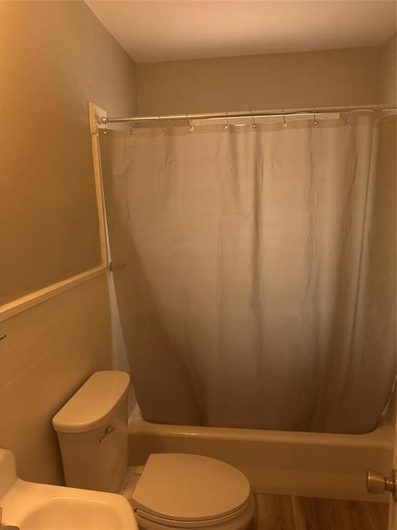 bathroom with shower / bath combination with curtain, wood-type flooring, and toilet