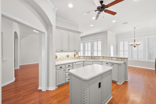 kitchen featuring light hardwood / wood-style floors, a kitchen island, crown molding, and sink