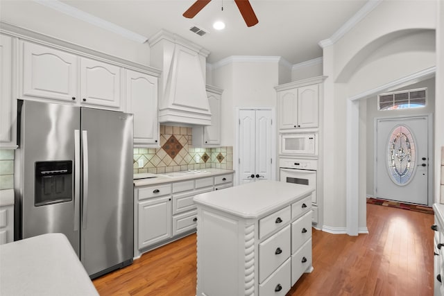 kitchen featuring white cabinets, custom exhaust hood, light hardwood / wood-style floors, and white appliances