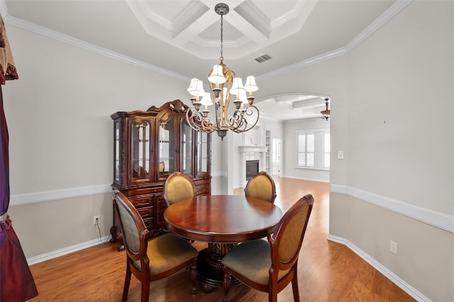 dining area with ceiling fan with notable chandelier, light wood-type flooring, ornamental molding, and coffered ceiling