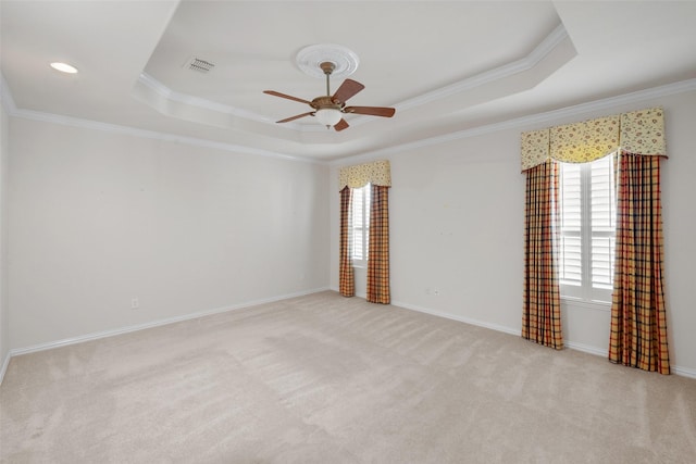 spare room with ceiling fan, a raised ceiling, crown molding, and light carpet