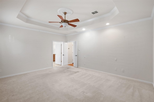 carpeted spare room with ceiling fan, a raised ceiling, and crown molding