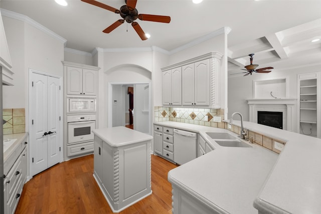 kitchen featuring beam ceiling, sink, white appliances, a kitchen island, and light wood-type flooring