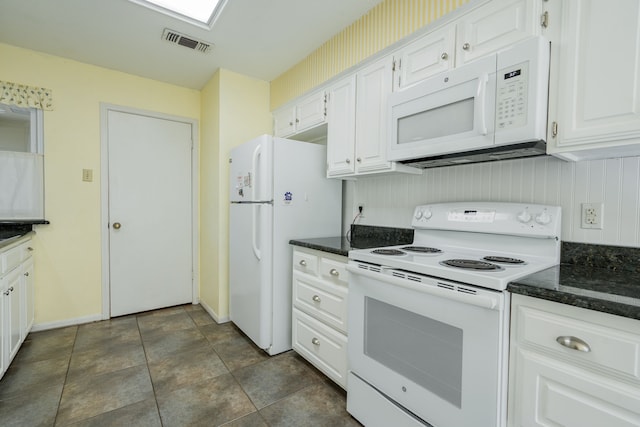 kitchen featuring dark stone counters, white appliances, visible vents, and white cabinetry