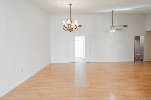 unfurnished room with high vaulted ceiling, visible vents, light wood-style flooring, and ceiling fan with notable chandelier