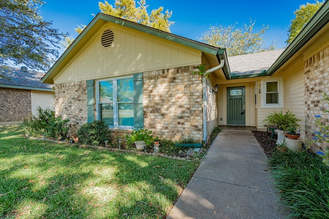 entrance to property featuring a yard and brick siding