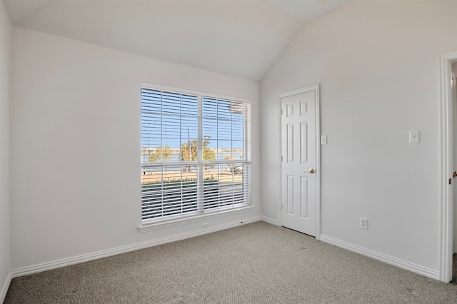 carpeted spare room with vaulted ceiling