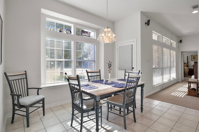 tiled dining room featuring an inviting chandelier and plenty of natural light