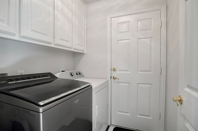 laundry room featuring separate washer and dryer and cabinets