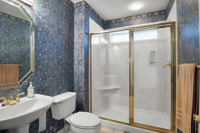 bathroom featuring a shower with door, toilet, sink, and tile patterned floors