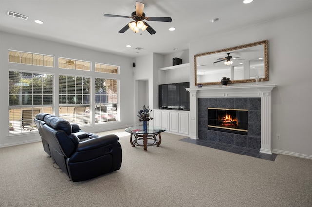 living room featuring ceiling fan, carpet floors, and a tile fireplace