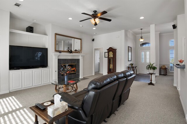 living room with crown molding, light carpet, a tiled fireplace, and ceiling fan