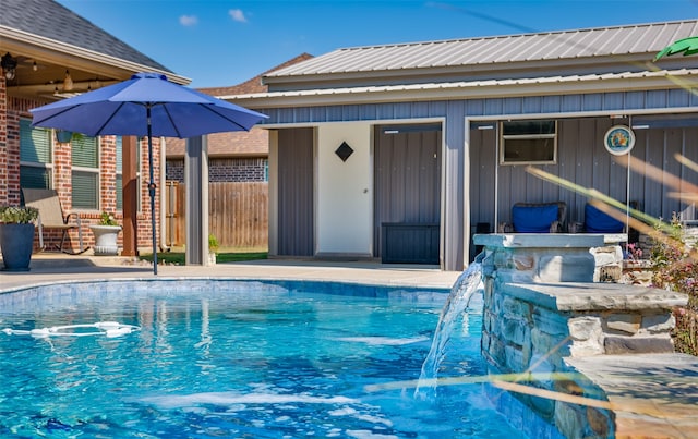 view of swimming pool featuring an outbuilding, pool water feature, and a patio