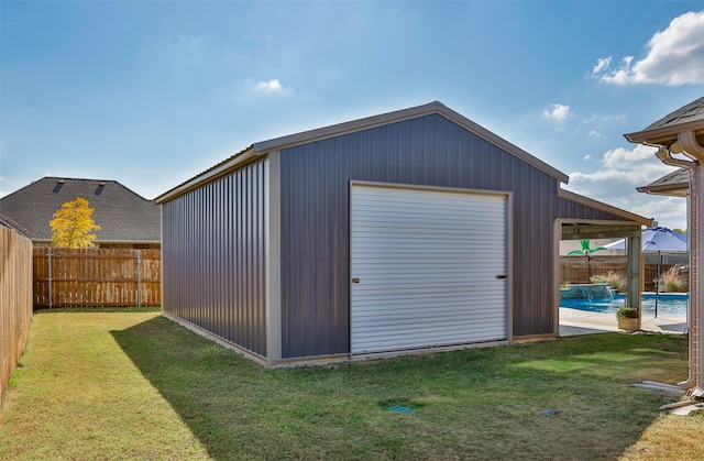 view of outdoor structure with a yard, pool water feature, a fenced in pool, and a garage