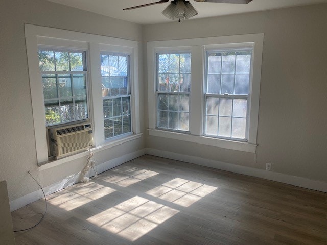 interior space with ceiling fan, cooling unit, and wood-type flooring