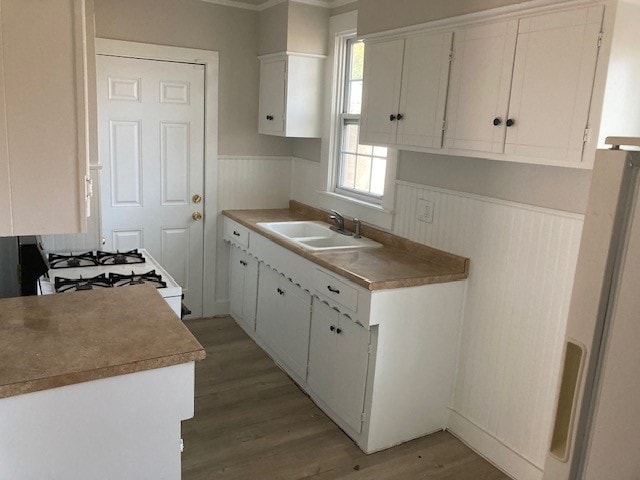 kitchen featuring refrigerator, white cabinetry, sink, hardwood / wood-style flooring, and gas range gas stove