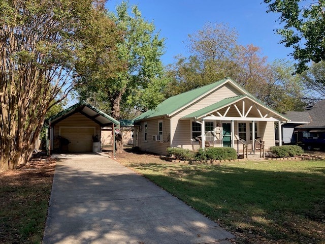 view of front of house with a front lawn, an outbuilding, a carport, covered porch, and a garage