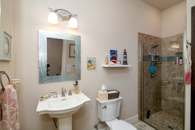 bathroom featuring a shower with door, sink, and toilet