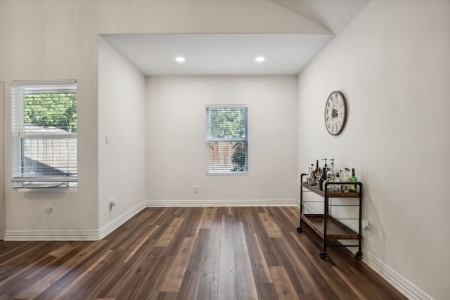 spare room featuring dark hardwood / wood-style flooring and bar area