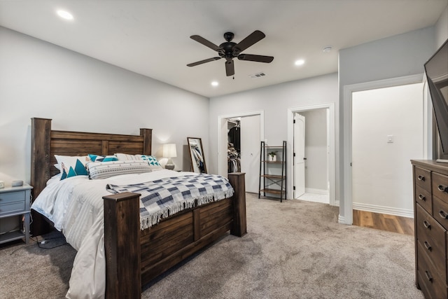 carpeted bedroom with a walk in closet, a closet, and ceiling fan