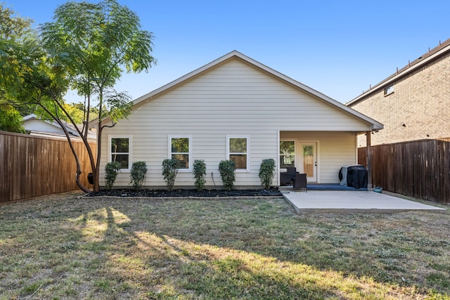 back of house with a patio area and a lawn